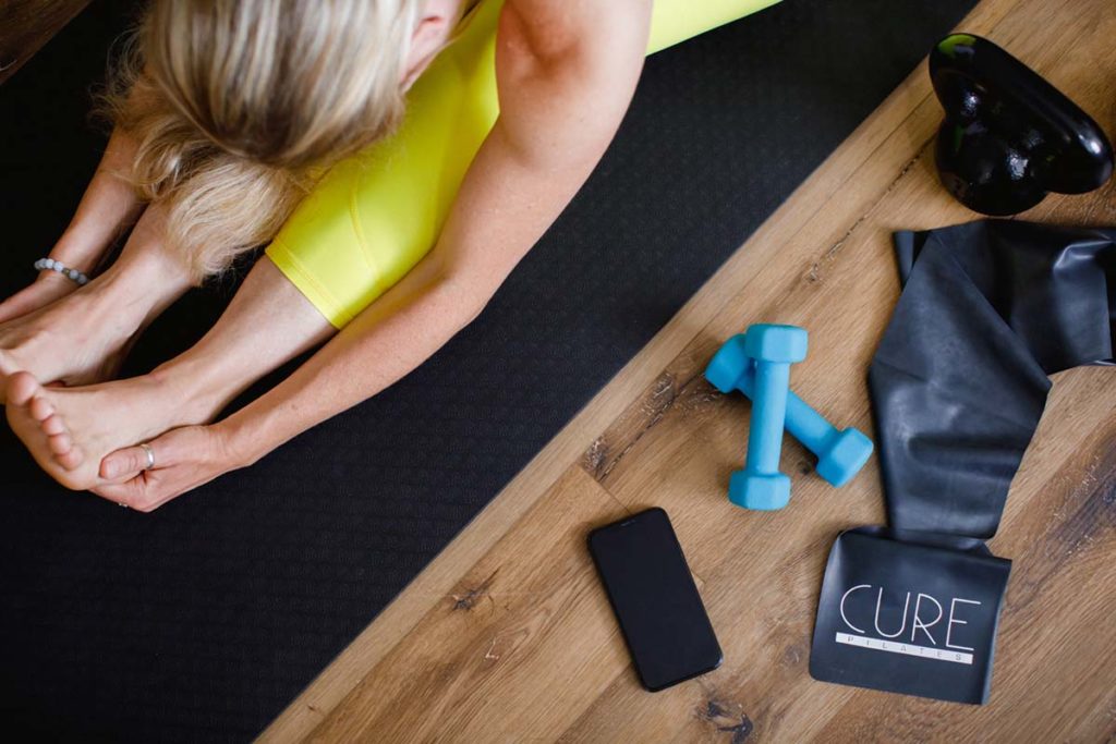 Woman exercising on a Pilates mat with fitness props around her